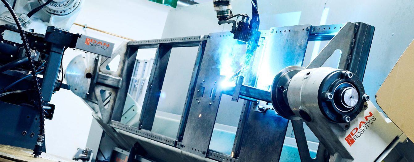 Robot welding a metal component in a fixture at Hosta.